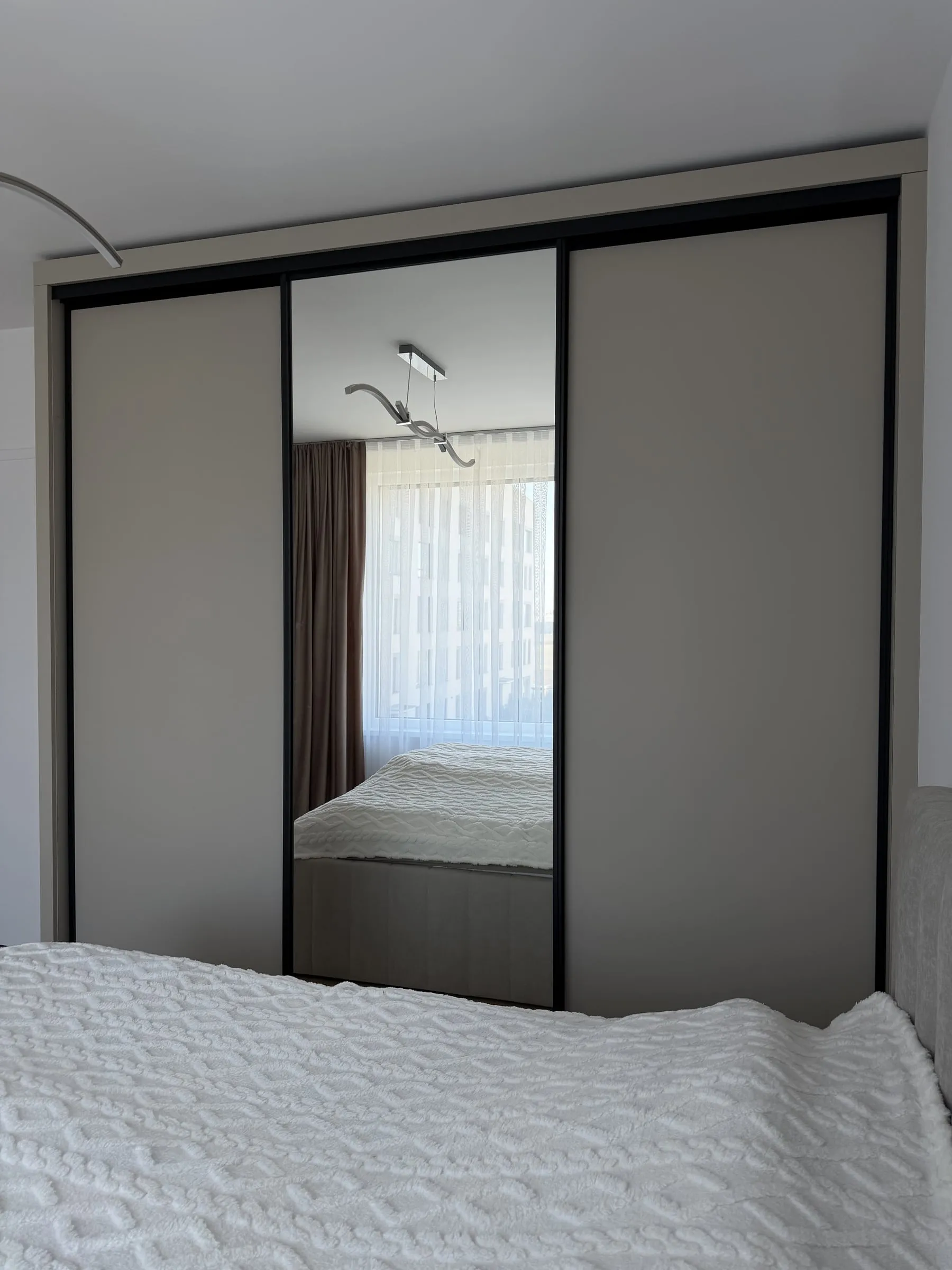 Tá istá skriňa spredu: v zrkadle sa odráža okno a posteľ