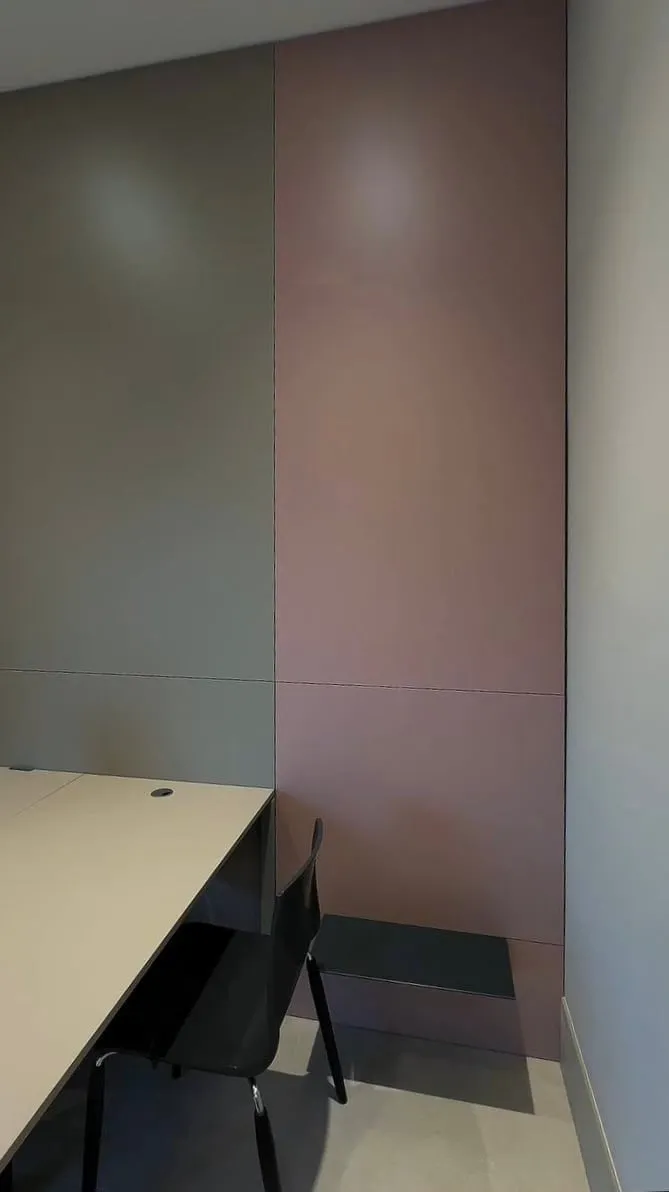 Sivý a ružový panel na stene, čierna polica a roh pracovnej dosky