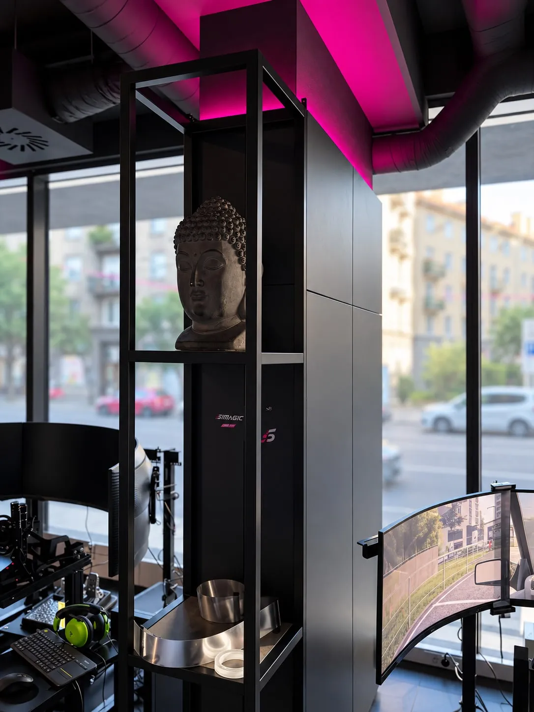 Čierny rámový regál s hlavou Budhu pri stĺpe obloženom čiernymi panelmi