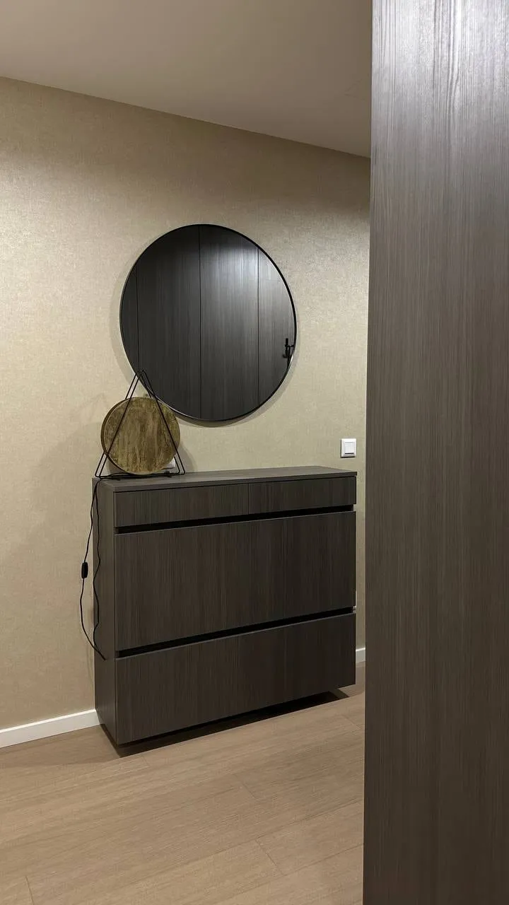 Komoda so zásuvkami v tmavom dreve a okrúhle zrkadlo nad ňou